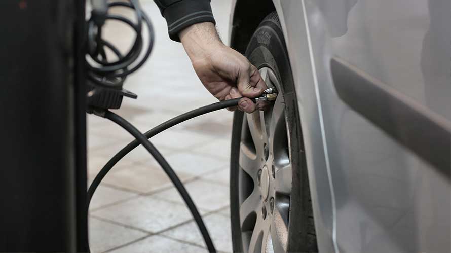 Pessoa colocando ar nos pneus traseiros de seu carro